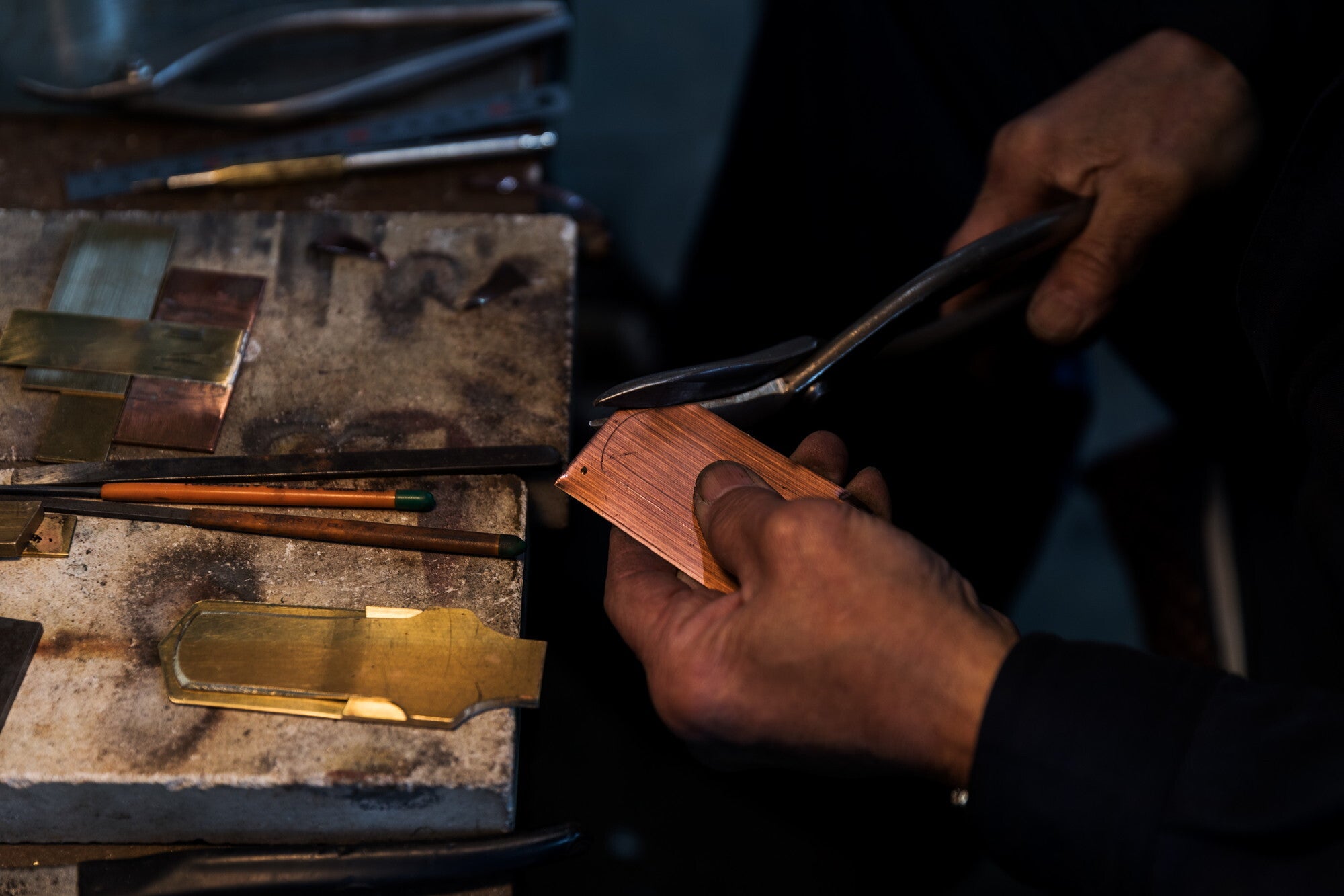 Person working with metal objects on a workbench in a workshop setting